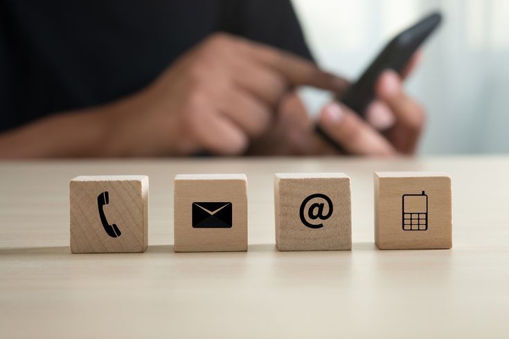 Contact us - wooden blocks with communication icons and smartphone representing connectivity